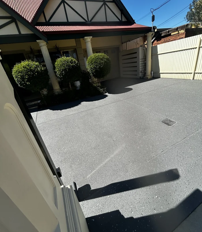 Dark grey resurfaced concrete driveway in front of a character home with columns