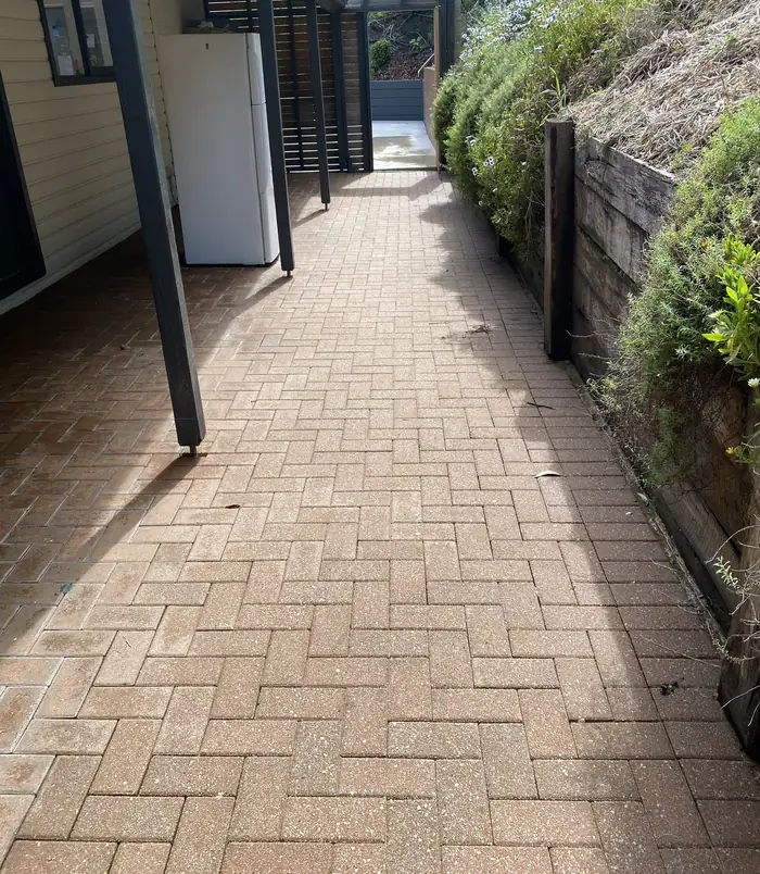Clean terracotta brick paver path beside a retaining wall after pressure washing