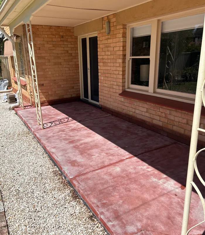 Dull, faded concrete patio beside a brick home with sliding doors, before resurfacing