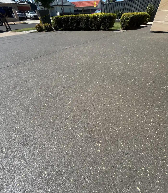 Matte dark grey resurfaced concrete with a clean, even finish beside a hedge
