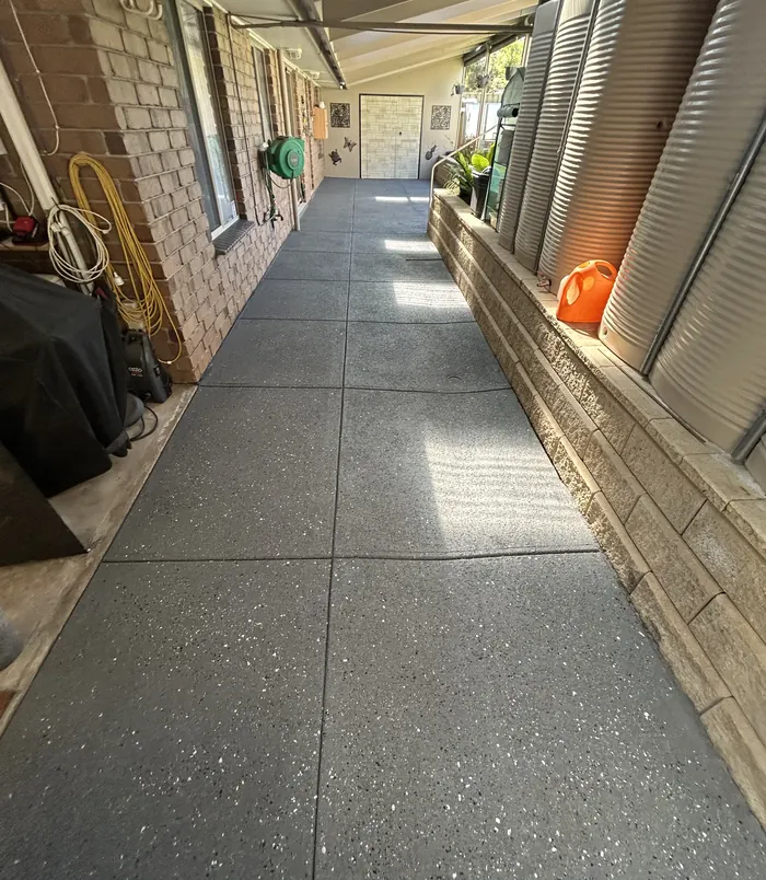Smooth grey resurfaced concrete walkway beside a brick wall and garden planter