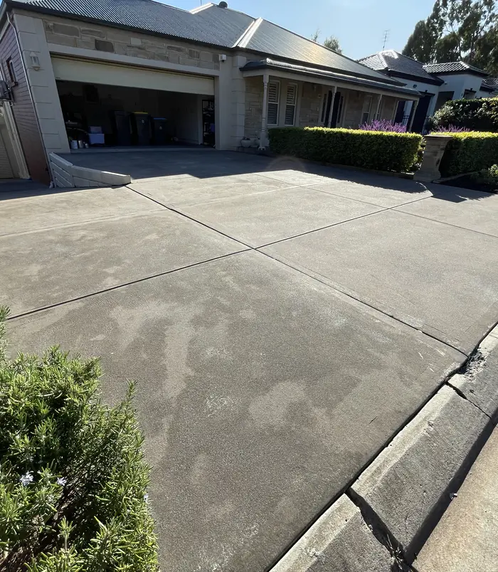 Pale, worn concrete driveway leading to a double garage, before concrete resurfacing