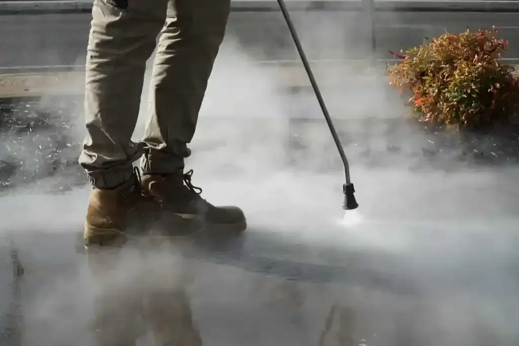 Surface Rescue team member in work boots using a pressure washer lance with a cloud of spray around the surface