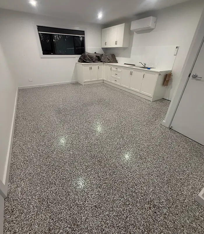 Speckled epoxy flake floor in a commercial kitchenette with white cabinetry