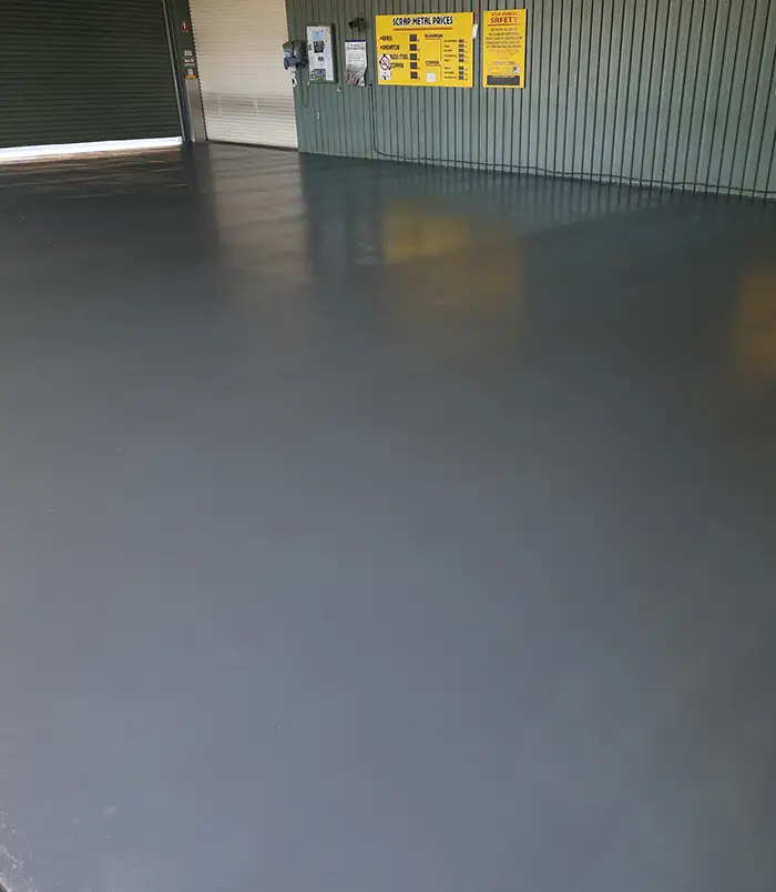 Smooth, glossy dark grey epoxy floor in an industrial building with yellow signs on the wall