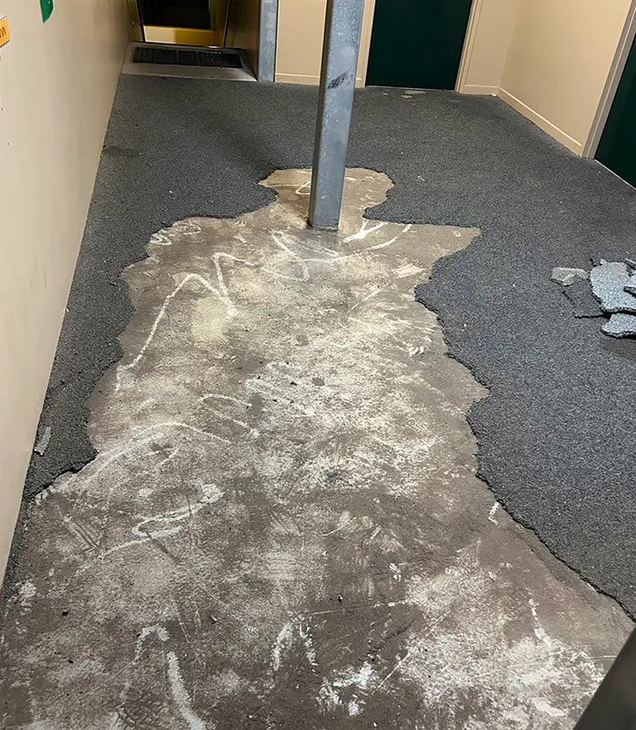 Worn, patchy concrete floor around a steel post with residue marks, before epoxy flooring