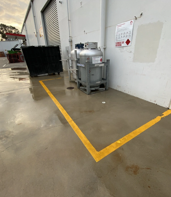Clean commercial concrete floor around a stainless steel tank with yellow line markings