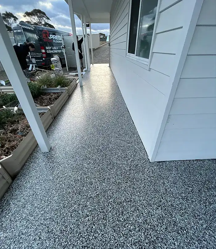 Speckled epoxy flake veranda floor beside a white weatherboard wall and garden planter