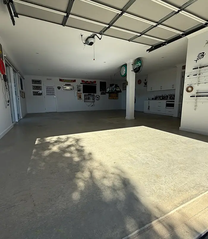 Dull concrete garage floor in a workshop with memorabilia on the walls, before epoxy flooring