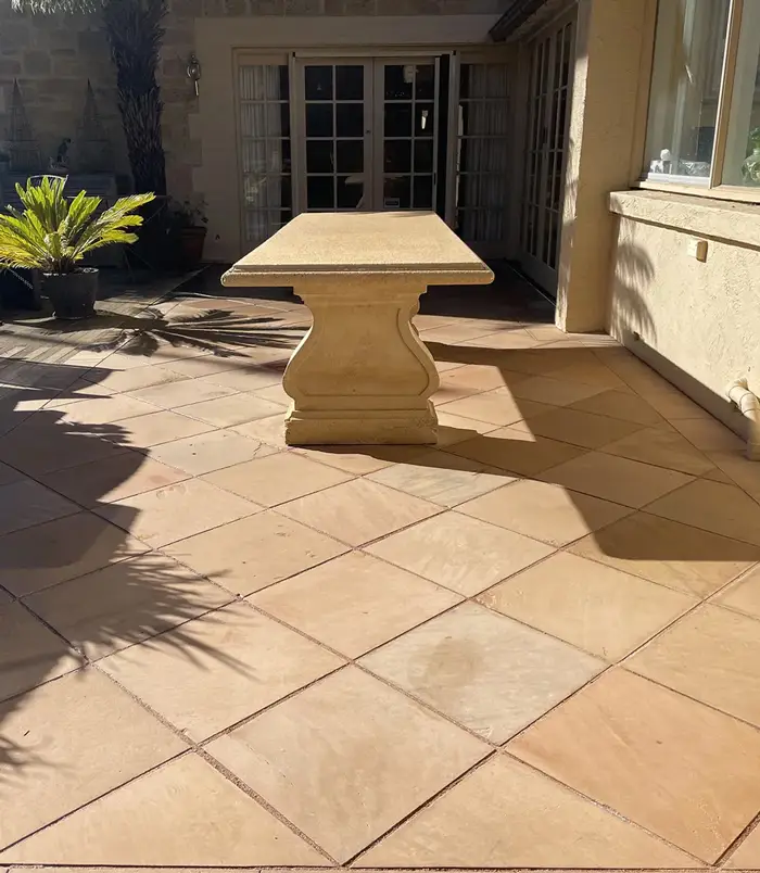 Clean terracotta pavers around a stone outdoor table beside French doors
