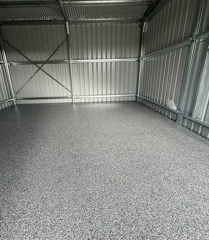Dark speckled epoxy flake floor in a large empty metal shed