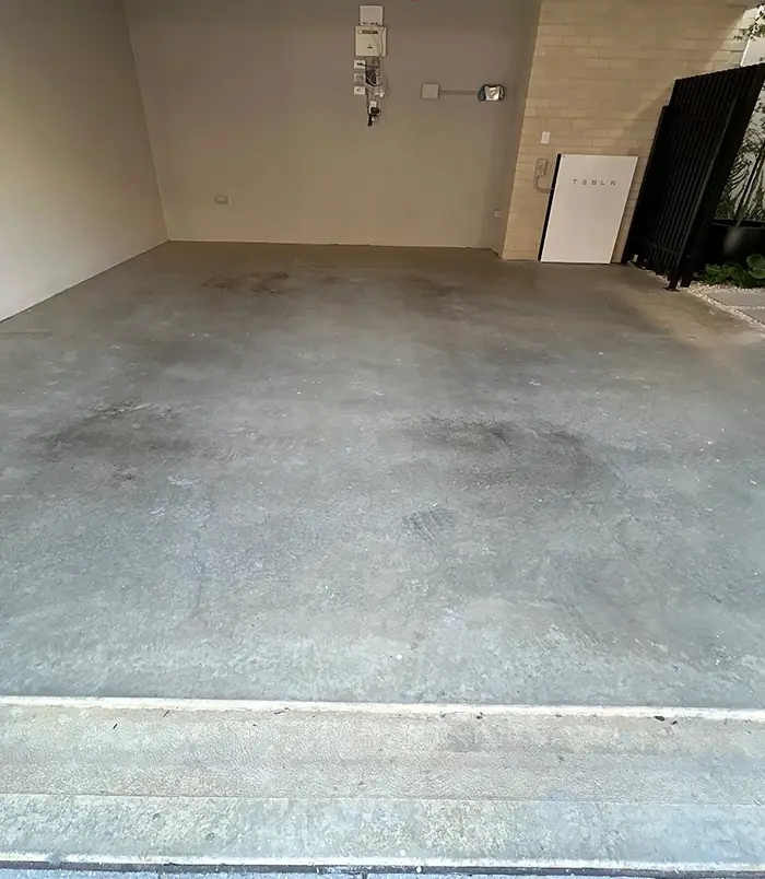 Stained concrete garage floor beside a side door, before epoxy flooring