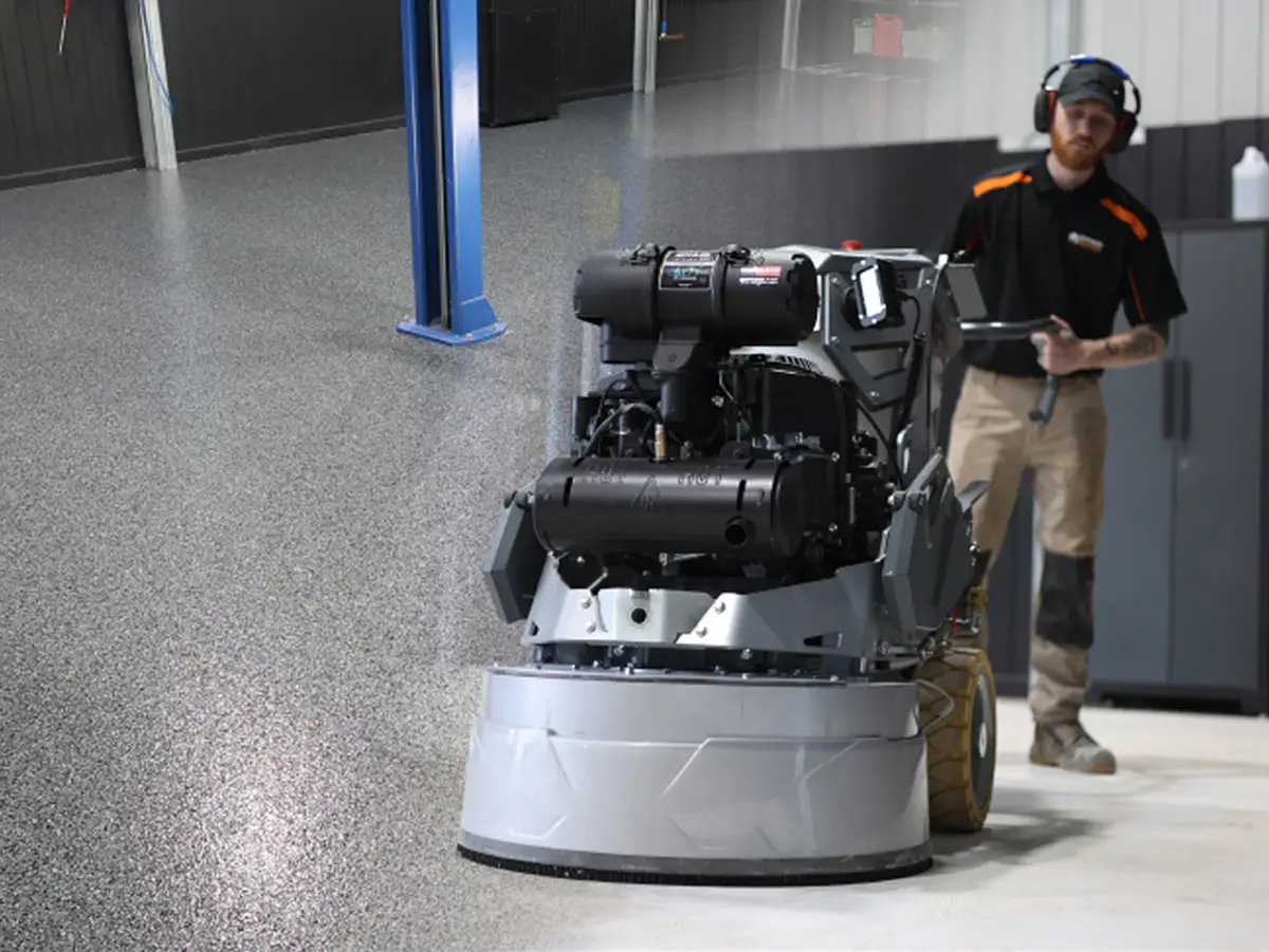 Surface Rescue technician standing beside a floor grinder on a pale concrete floor