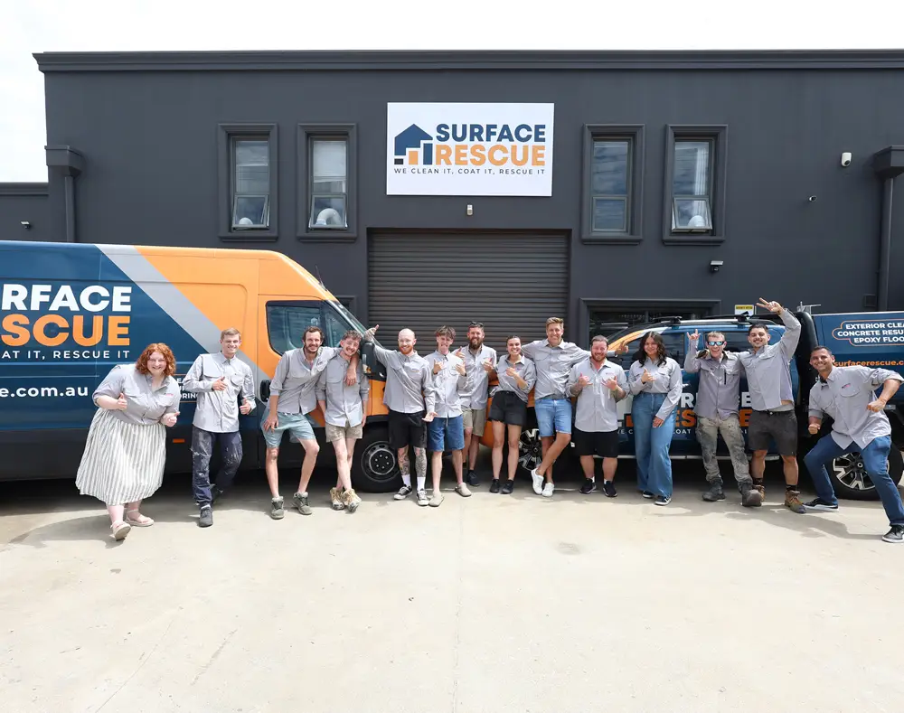 Large group of Surface Rescue team members standing in front of a workshop and branded service van