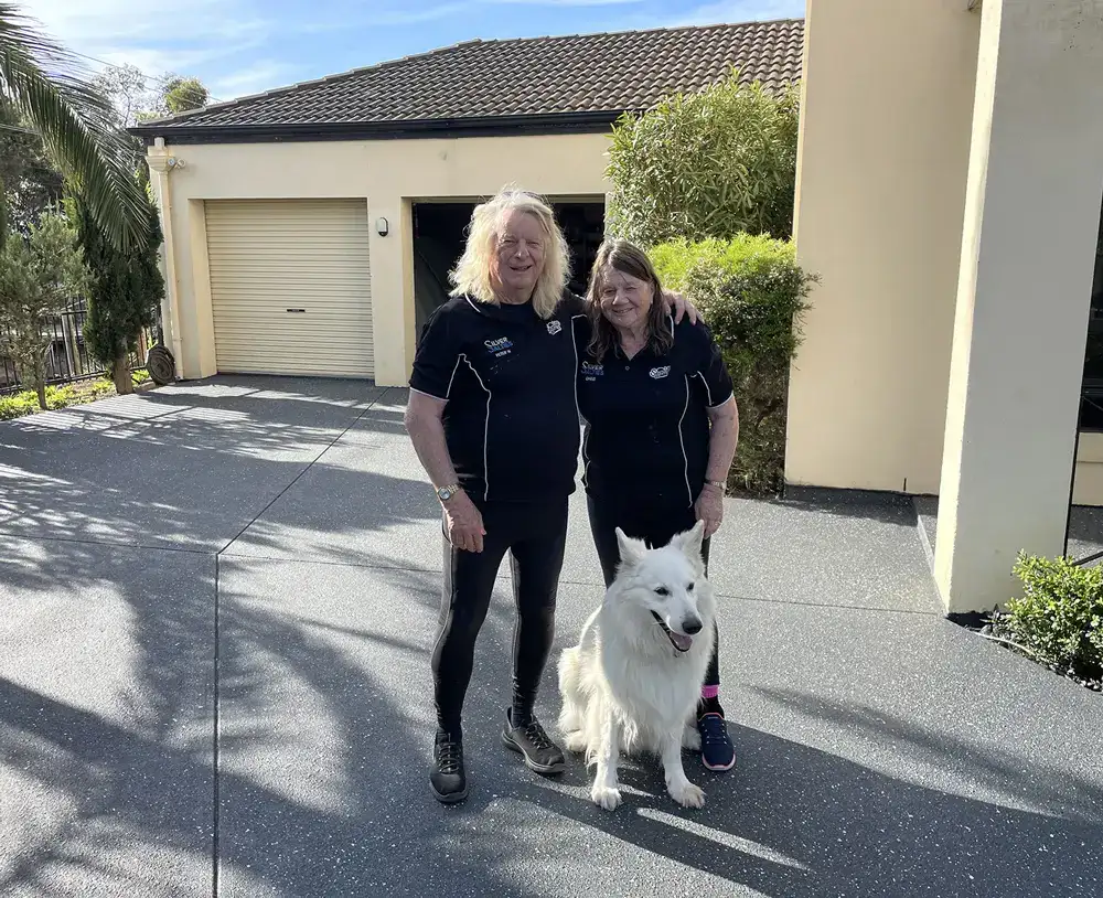 Two happy clients standing on their newly resurfaced driveway