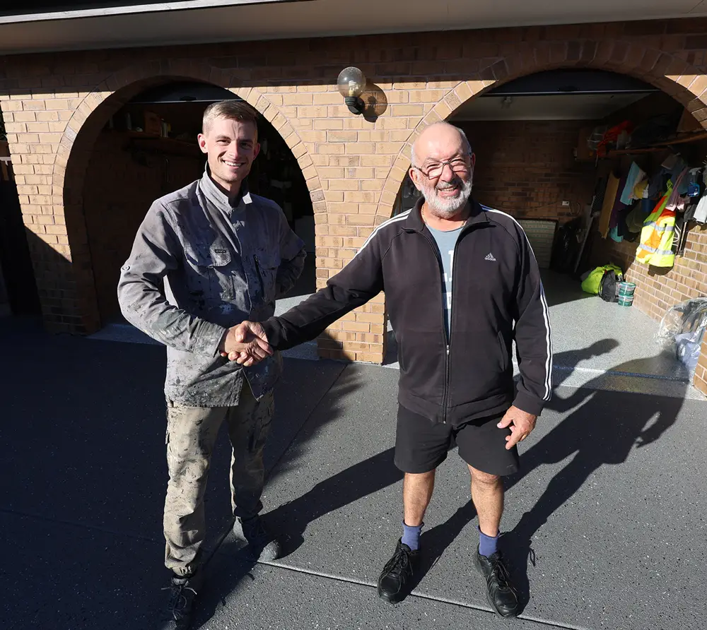 Surface Rescue team member shaking hands with a customer in front of a brick home