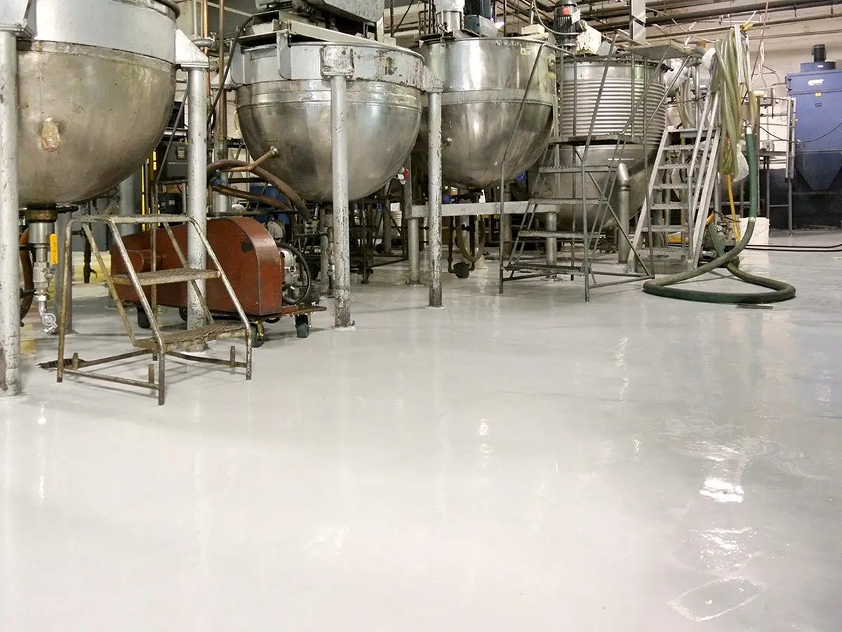 Glossy white epoxy floor in a food production facility with stainless steel mixing tanks