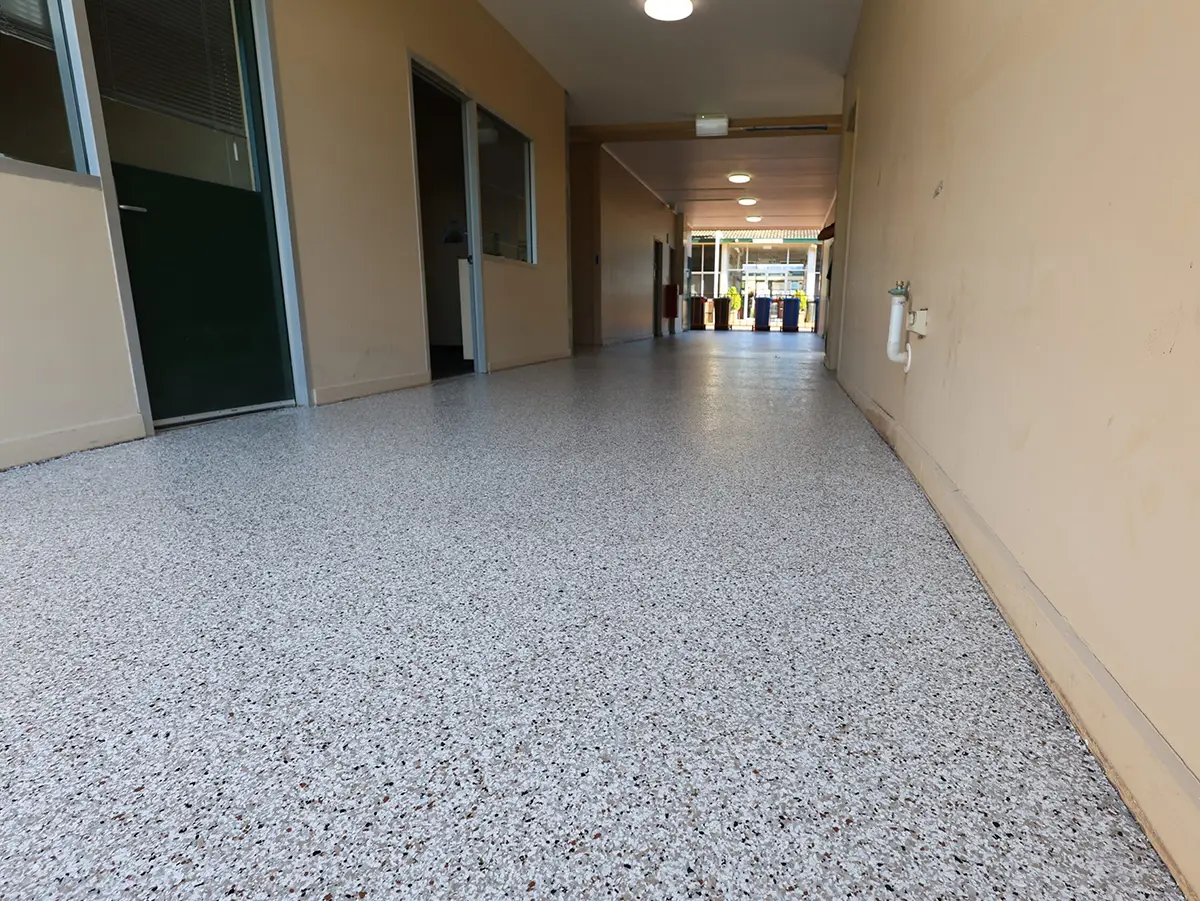 Long covered walkway with a speckled epoxy flake floor leading to an open doorway