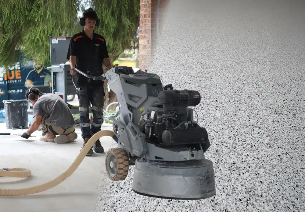Surface Rescue technician wearing ear protection operating a floor grinder on a speckled floor
