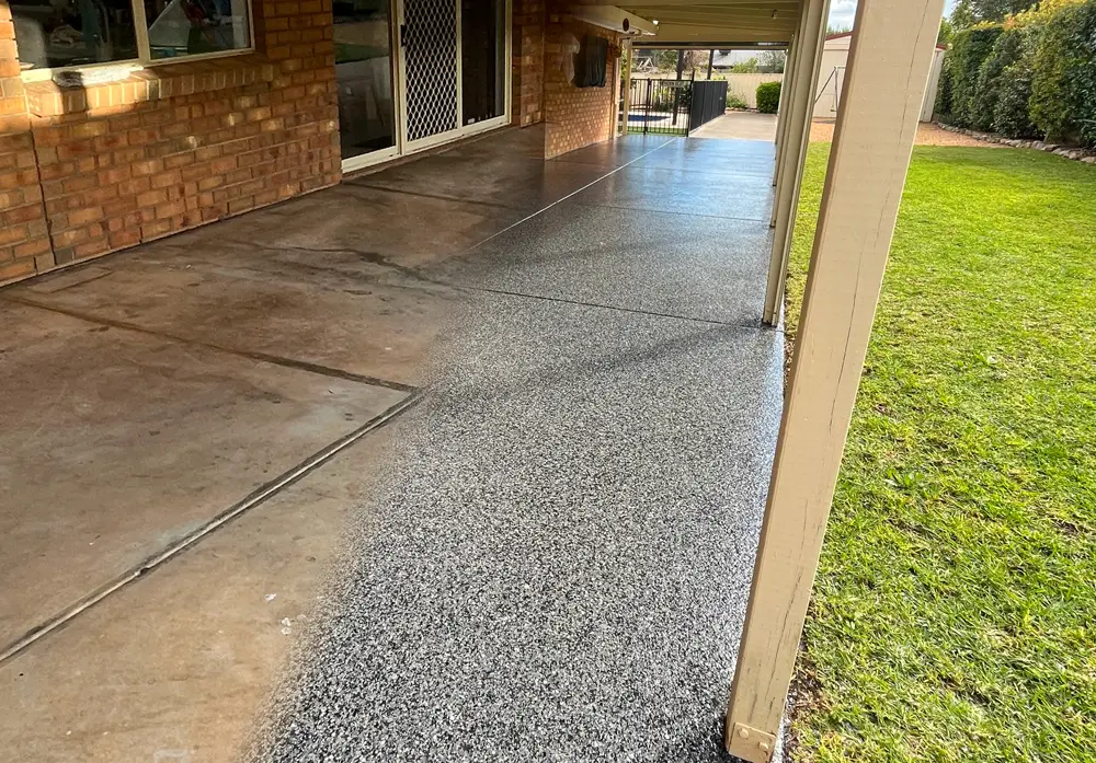 Veranda floor beside a brick wall and white post showing transition from old, worn surface to new surface