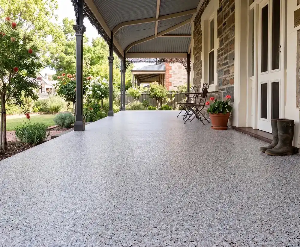 Speckled epoxy flake veranda floor in front of a heritage sandstone home with garden beyond
