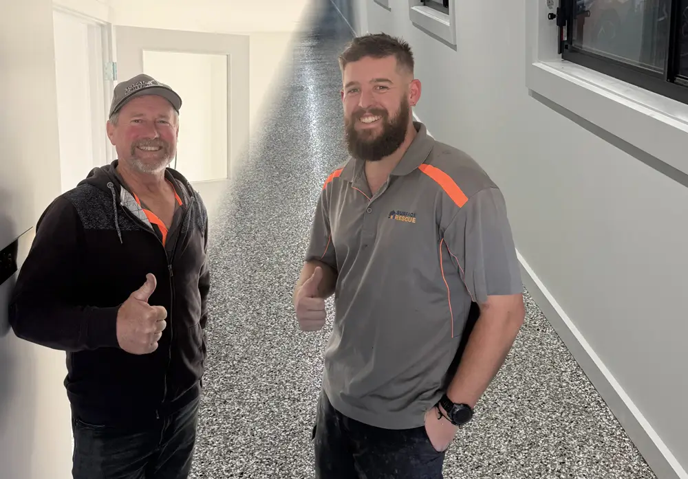 Two smiling Surface Rescue team members giving thumbs up beside a speckled epoxy flake floor