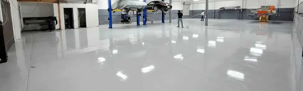 Glossy white epoxy floor in a large workshop with vehicle hoists