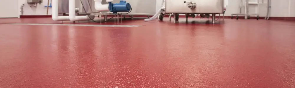 Glossy red epoxy floor coating with equipment in the background
