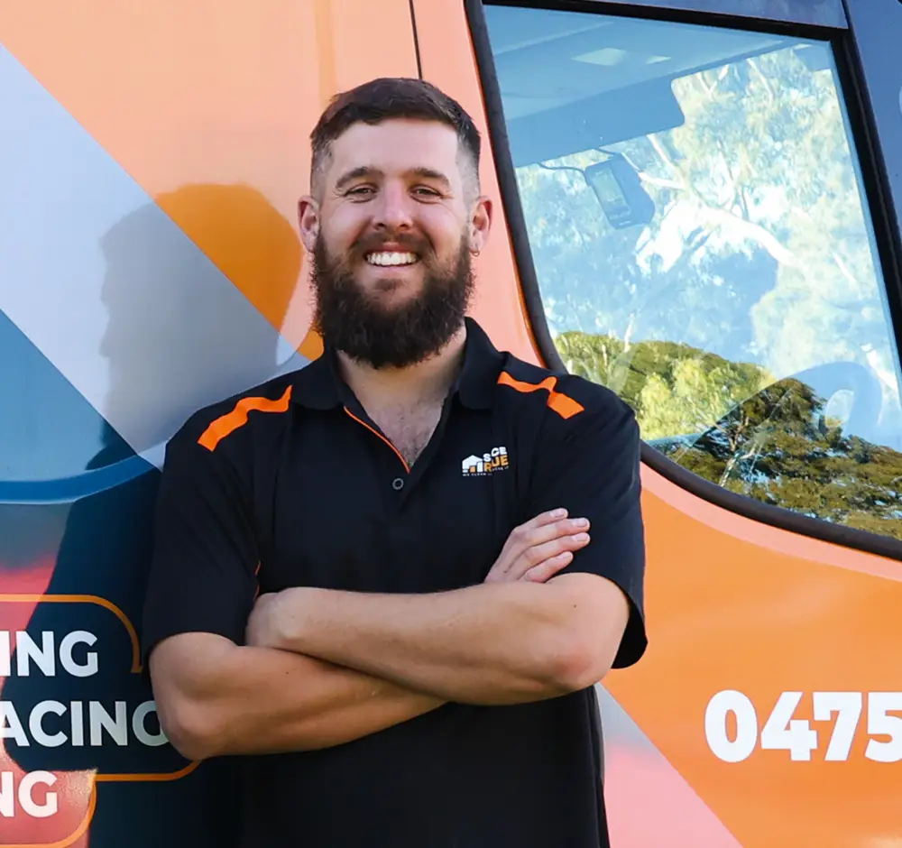Smiling Surface Rescue team member with arms crossed in front of an orange branded van