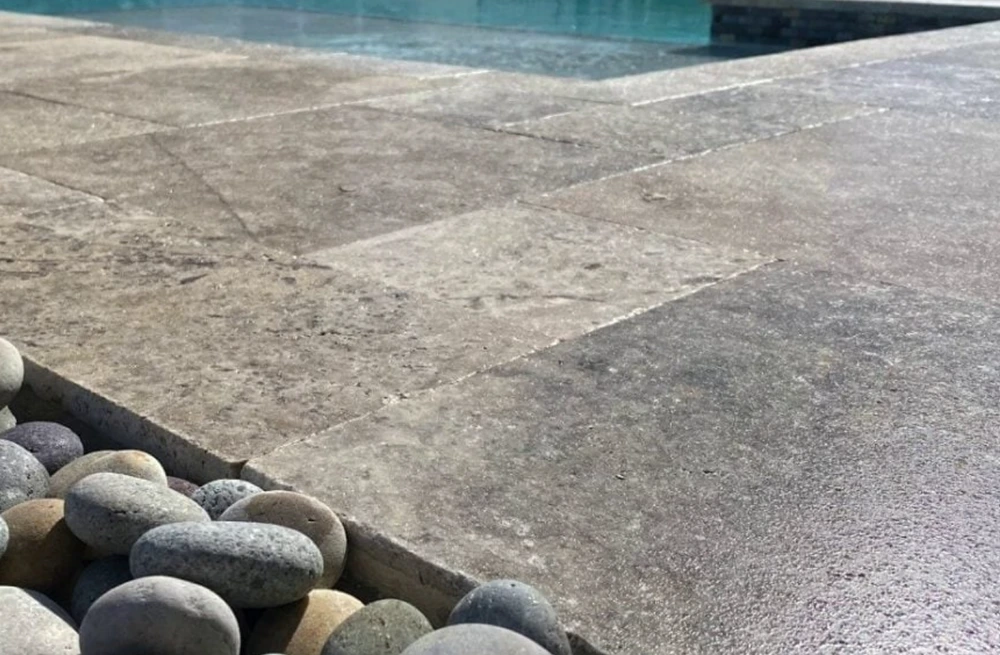 Close-up of grey stamped-pattern concrete paving beside a pool edge