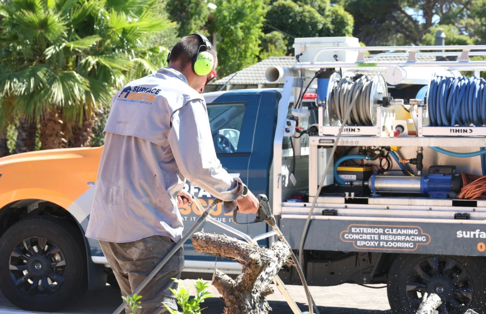 Surface Rescue technician wearing ear protection beside a truck-mounted pressure washing unit