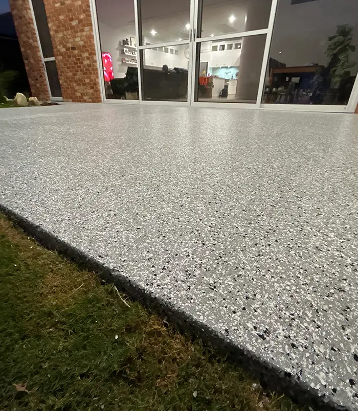 Light grey speckled epoxy flake patio floor beside glass doors