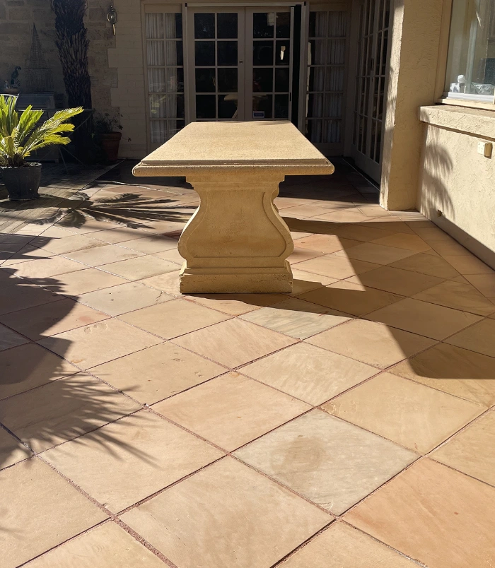 Clean terracotta pavers around a stone outdoor table beside French doors