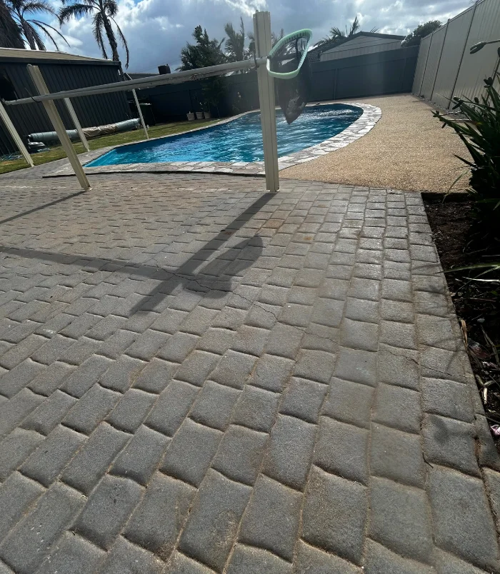 Worn brick paving around a freeform swimming pool, before pool resurfacing