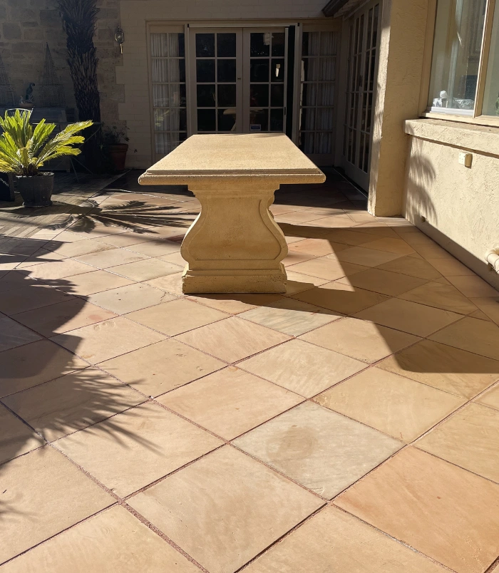 Clean terracotta pavers around a stone outdoor table beside French doors after pressure washing