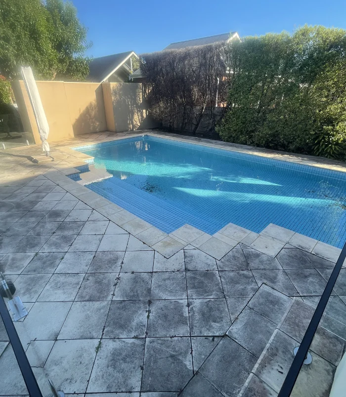 Dirty, discoloured pool surround and steps beside a swimming pool, before pressure washing
