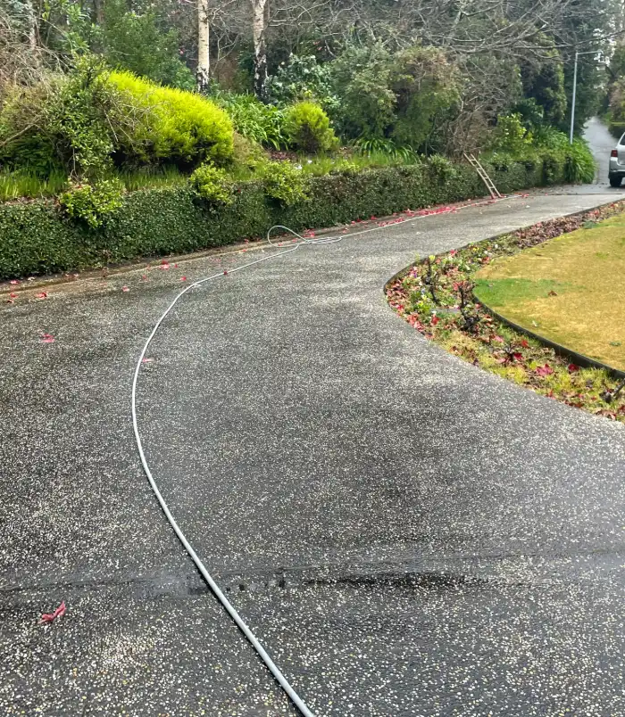 Curved exposed aggregate driveway before sealing, looking dull, weathered and uneven in colour